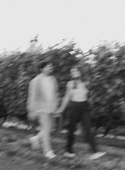 A blurry black and white photo of the couple walking through a vineyard