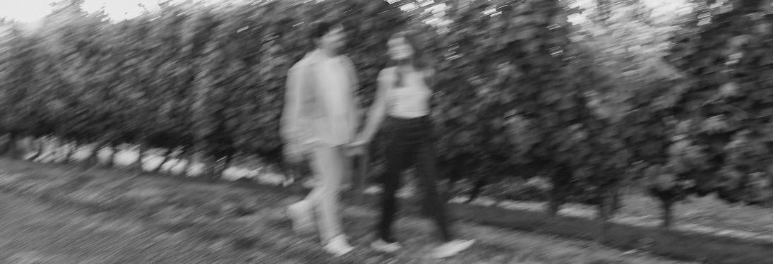 A blurry black and white photo of the couple walking through a vineyard