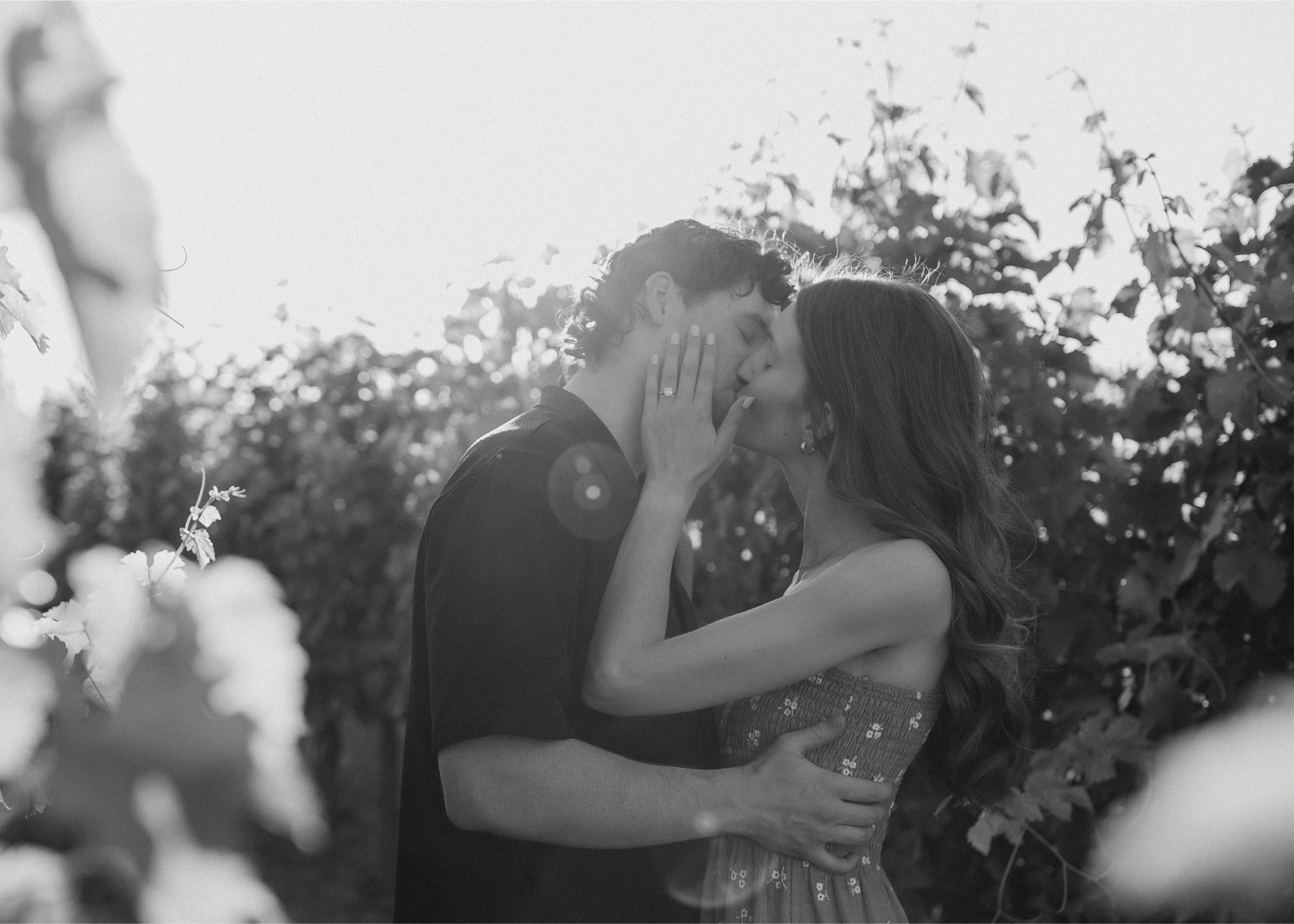 A black and white photo of the couple kissing