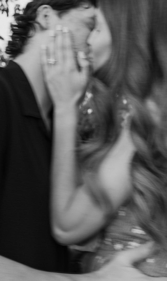 A black and white photo of the couple kissing